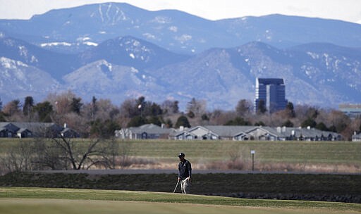 A golfer sets up a chip shot on to a green at Commonground Golf Course that will close Thursday, March 26, as part of a &quot;stay at home&quot; order to reduce the spread of the new coronavirus Wednesday, March 25, 2020, in Aurora, Colo. The new coronavirus causes mild or moderate symptoms for most people, but for some, especially older adults and people with existing health problems, it can cause more severe illness or death. (AP Photo/David Zalubowski)