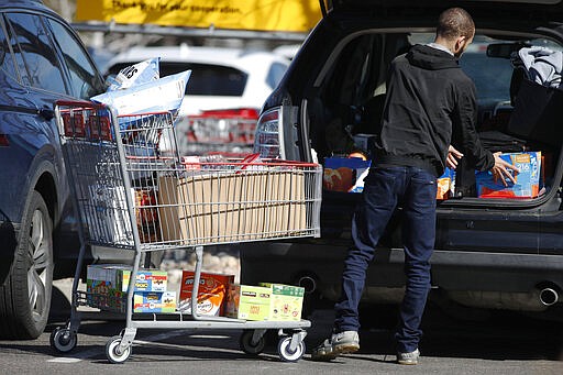 A shopper loads boxes of items into the back of his sports-utility vehicle outside a Costco warehouse as residents are ordered to &quot;stay at home&quot; to reduce the spread of the new coronavirus Wednesday, March 25, 2020, in Aurora, Colo. The new coronavirus causes mild or moderate symptoms for most people, but for some, especially older adults and people with existing health problems, it can cause more severe illness or death. (AP Photo/David Zalubowski)