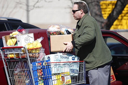 A shopper unloads his cart outside a Costco warehouse as residents deal with a &quot;stay at home&quot; order to reduce the spread of the new coronavirus Wednesday, March 25, 2020, in Aurora, Colo. The new coronavirus causes mild or moderate symptoms for most people, but for some, especially older adults and people with existing health problems, it can cause more severe illness or death. (AP Photo/David Zalubowski)