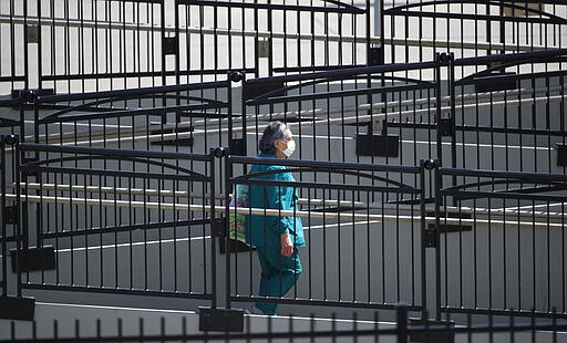 A woman wearing a surgical mask winds her way along the stairs leading from the central bus station as people try to reduce the spread of the new coronavirus Wednesday, March 25, 2020, in Aurora, Colo. The new coronavirus causes mild or moderate symptoms for most people, but for some, especially older adults and people with existing health problems, it can cause more severe illness or death. (AP Photo/David Zalubowski)