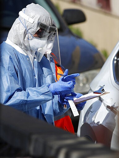 A medical technician inserts a swab into a container after administering a test for the new coronavirus to a patient in the drive-thru testing lane outside Stride Community Health Wednesday, March 25, 2020, in Aurora, Colo. The new coronavirus causes mild or moderate symptoms for most people, but for some, especially older adults and people with existing health problems, it can cause more severe illness or death. (AP Photo/David Zalubowski)