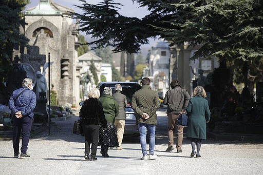 FILE - In this Tuesday, March 17, 2020 file photo, relatives walk behind a hearse carrying a coffin inside the Monumentale cemetery, in Bergamo, Italy. It was the biggest soccer game in Atalanta&#146;s history and a third of Bergamo&#146;s population made the short trip to Milan&#146;s famed San Siro Stadium to witness it. Nearly 2,500 fans of visiting Spanish club Valencia also traveled to the Champions League match. More than a month later, experts are pointing to the Feb. 19 game as one of the biggest reasons why Bergamo has become one of the epicenters of the coronavirus pandemic &#151; a &#147;biological bomb&#148; was the way one respiratory specialist put it &#151; and why 35% of Valencia&#146;s team became infected. The new coronavirus causes mild or moderate symptoms for most people, but for some, especially older adults and people with existing health problems, it can cause more severe illness or death. (AP Photo/Luca Bruno, File)