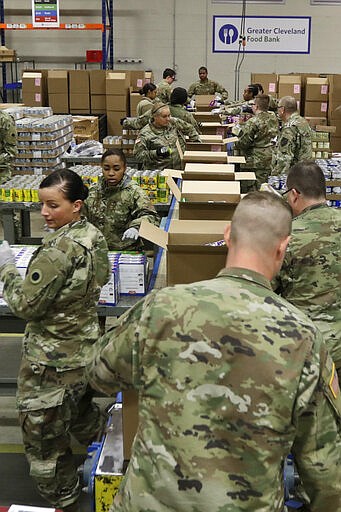 Members of The Ohio National Guard assist in repackaging emergency food boxes for food distribution at the Cleveland Food Bank, Tuesday, March 24, 2020, in Cleveland.  State parks have shuttered cabins, golf courses and marinas as Ohio enters its first full day of a statewide &#147;stay at home&#148; order to slow the spread of the coronavirus. Grocery stores, gas stations and other essential businesses remain open. (AP Photo/Tony Dejak)