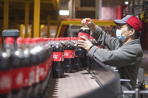 This Tuesday, March 24, 2020, photo released by China's Xinhua News Agency, shows a worker wearing a face mask on a production line at a Swire Coca-Cola Beverages Hubei Limited plant in Wuhan in central China's Hubei Province. According to Chinese state media, the plant restarted some production lines on Monday. While many migrant workers across China remain trapped by travel bans due to the coronavirus, some industrial production has returned to action, including in the crucial auto manufacturing industry, which is largely based in Wuhan, and in businesses that provide critical links in global supply chains. The new coronavirus causes mild or moderate symptoms for most people, but for some, especially older adults and people with existing health problems, it can cause more severe illness or death. (Xiao Yijiu/Xinhua via AP)