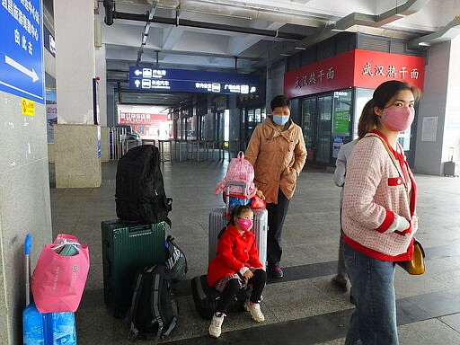 Travelers wearing masks wait at a railway station in Yichang in central China's Hubei province Wednesday, March 25, 2020. Trains carrying factory employees back to work after two months in locked-down cities rolled out of Hubei province, the center of China's virus outbreak, as the government on Wednesday began lifting the last of the controls that confined tens of millions of people to their homes. (Chinatopix Via AP)