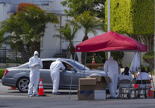 Unidentified Los Angeles residents are admistered with a test for COVID-19 while in their vehicles inside the Crenshaw Christian Center in South Los Angeles Wednesday, March 25, 2020. With California virus cases surging, Gov. Gavin Newsom said his stay-at-home order for 40 million Californians may stay in place into May.  (AP Photo/Damian Dovarganes)