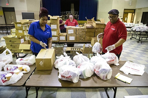 School staff pack grab-and-go meals for distribution to students and families at John H. Webster Elementary School in Philadelphia, Wednesday, March 25, 2020. (AP Photo/Matt Rourke)