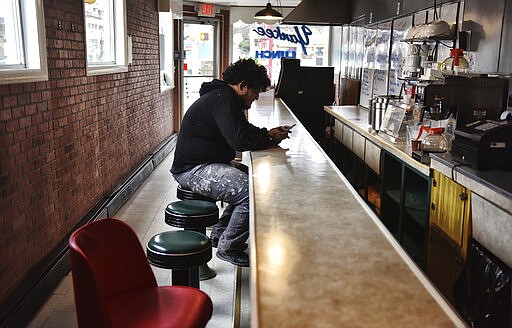 Gocq Sogal, 24, of Scranton, Pa. waits for a take-out order during his lunch break at La Campasina Mexican restaurant in Scranton, Pa. Tuesday, March 24, 2020. Restaurants state-wide have been ordered by Gov. Tom Wolf to close all dine in operations and offer take-out and delivery services only to mitigate the spread of the COVID-19 virus.  (Sean McKeag /The Times Tribune via AP)