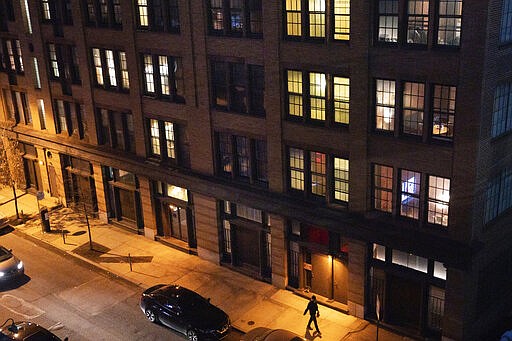 In this Tuesday evening, March 24, 2020 photo, a pedestrian walks down a quiet street in Old City in Philadelphia. Non-essential businesses are closed and a stay-at-home order has been issued by the city, with exceptions to allow people to purchase essential goods and food or seek medical attention, the order was put in place try and reduce the spread of the Coronavirus in Philadelphia. Outdoor activities such as walking, running, cycling, are permitted under the stay at home order. (Jessica Griffin/The Philadelphia Inquirer via AP)