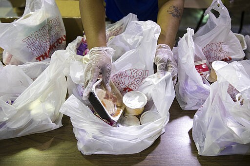 School staff pack grab-and-go meals for distribution to students and families at John H. Webster Elementary School in Philadelphia, Wednesday, March 25, 2020. (AP Photo/Matt Rourke)