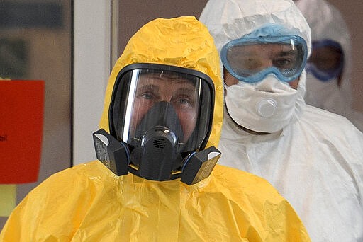 Russian President Vladimir Putin wearing a protective suit enters a hall during his visit to the hospital for coronavirus patients in Kommunarka, outside Moscow, Russia, Tuesday, March 24, 2020. For some people the COVID-19 coronavirus causes mild or moderate symptoms, but for some it can cause severe illness including pneumonia. (Alexei Druzhinin, Sputnik, Kremlin Pool Photo via AP)