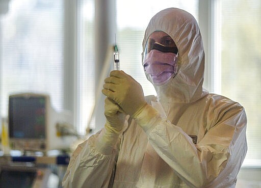 A medical staffer of the Intensive Care Unit of the Casalpalocco COVID-19 Clinic in the outskirts of Rome checks a syringe, Wednesday, March 25, 2020. The new coronavirus causes mild or moderate symptoms for most people, but for some, especially older adults and people with existing health problems, it can cause more severe illness or death. (AP Photo/Domenico Stinellis)