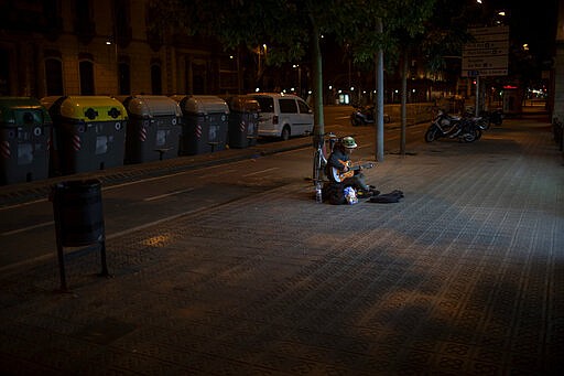 In this Saturday, March 21, 2020 photo, Kevin, 32, from France, plays guitar in front of a supermarket in Barcelona, Spain. Kevin, who has slept on the streets of Barcelona for the last 4 years said &quot;I used to earn enough money to eat every day, now I don't get even one meal a day. Now I play the guitar just for me as nobody is in the street&quot;. While Spanish authorities tell the public that staying home is the best way to beat the coronavirus pandemic, some people are staying out because home has come to mean the streets of Madrid and Barcelona. (AP Photo/Emilio Morenatti)