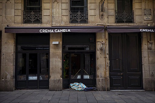 In this Saturday, March 21, 2020 photo, Jose sleeps in the street in downtown Barcelona, Spain. Jose, 27, has been sleeping in the street for 5 years and is convinced that the Spanish army will put all the beggars of the city in tents &quot;I refuse! I am not going to be infested with the virus anywhere, I am safe here in the arcade&quot;. Authorities are scrambling to get as many homeless people off the streets without cramming them into a shelter, where the spread of COVID-19 could be even greater. (AP Photo/Emilio Morenatti)