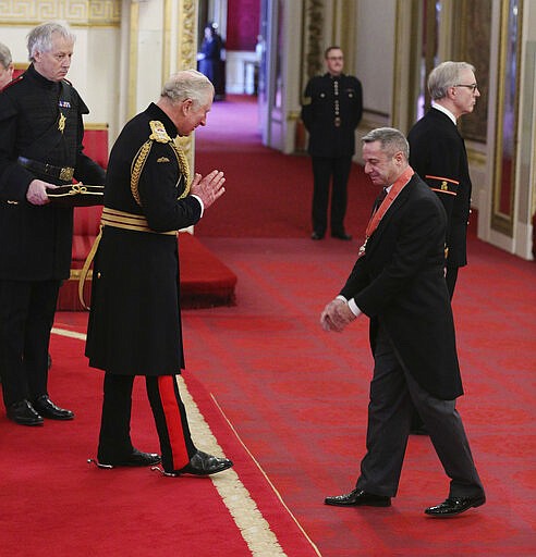 FILE - In this March 12, 2020 file photo, Stephen Mear, right, receives his CBE from Britain's Prince Charles, during an investiture ceremony at Buckingham Palace, London. Prince Charles, the heir to the British throne, has tested positive for the new coronavirus. The prince&#146;s Clarence House office reported on Wednesday, March 25, 2020 that the 71-year-old is showing mild symptoms of COVID-19 and is self-isolating at a royal estate in Scotland. It says his wife Camilla has tested negative.(Yui Mok/PA via AP, File)