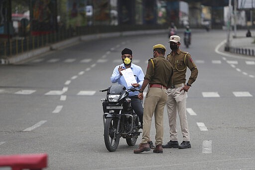 Policemen check papers of a commuter during lockdown in Jammu, India, Wednesday, March 25, 2020. The world's largest democracy went under the world's biggest lockdown Wednesday, with India's 1.3 billion people ordered to stay home in a bid to stop the coronavirus pandemic from spreading and overwhelming its fragile health care system as it has done elsewhere. For most people, the new coronavirus causes mild or moderate symptoms, such as fever and cough that clear up in two to three weeks. For some, especially older adults and people with existing health problems, it can cause more severe illness, including pneumonia and death. (AP Photo/Channi Anand)