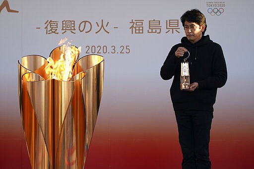 An official holds a lantern containing the Olympic Flame at the end of a flame display ceremony in Iwaki, northern Japan, Wednesday, March 25, 2020. IOC President Thomas Bach has agreed &quot;100%&quot; to a proposal of postponing the Tokyo Olympics for about one year until 2021 because of the coronavirus outbreak. (AP Photo/Eugene Hoshiko)