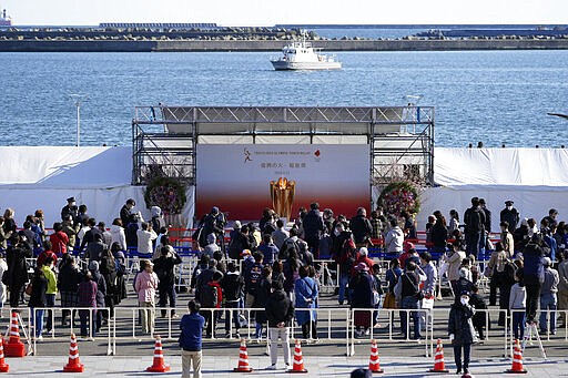 Visitors queue to see the Olympic Flame during a flame display ceremony in Iwaki, Fukushima Prefecture, northern Japan, Wednesday, March 25, 2020. IOC President Thomas Bach has agreed &quot;100%&quot; to a proposal of postponing the Tokyo Olympics for about one year until 2021 because of the coronavirus outbreak. (AP Photo/Eugene Hoshiko)