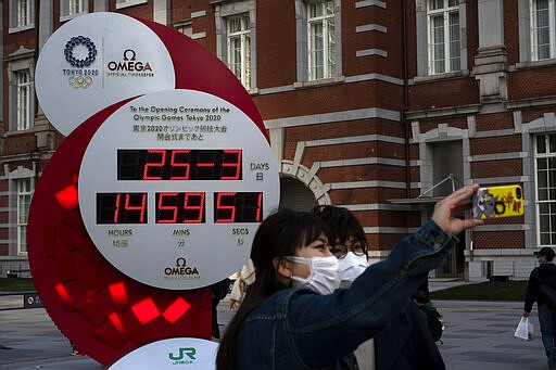 Two women take a selfie with a Tokyo 2020 countdown clock displaying the current date and time outside Tokyo Station, Wednesday, March 25, 2020, in Tokyo. Not even the Summer Olympics could withstand the force of the coronavirus. After weeks of hedging, the IOC took the unprecedented step of postponing the world's biggest sporting event, a global extravaganza that's been cemented into the calendar for more than a century. (AP Photo/Jae C. Hong)