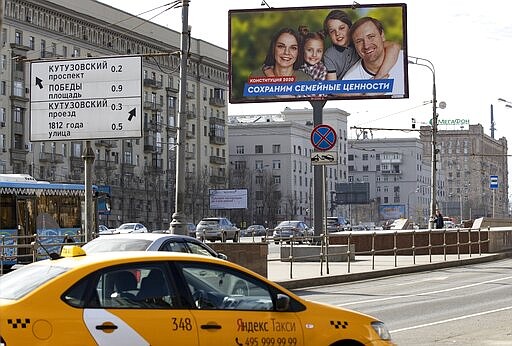 Cars drive past a billboard that reads: &quot;Let's preserve traditional values&quot;, in a street in Moscow, Russia, Wednesday, March 25, 2020. Russian President Vladimir Putin has postponed a nationwide vote on proposed constitutional amendments that include a change potentially allowing him to stay in office until 2036. Putin cited the coronavirus in announcing the postponement of the vote that was originally scheduled for April 22. (AP Photo/Alexander Zemlianichenko)