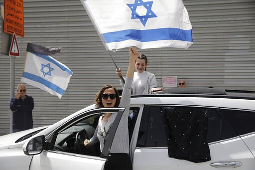 Israelis hold national flags during a protest against Prime Minister Benjamin Netanyahu outside the national parliament in Jerusalem, Monday, March 23, 2020. The opposition has accused Netanyahu of using the coronavirus crisis as cover to undermine the country's democratic institutions. With the country in near-shutdown mode, Netanyahu has already managed to postpone his own pending criminal trial and authorize unprecedented electronic surveillance of Israeli citizens. (AP Photo/Sebastian Scheiner)