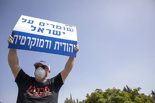 An Israeli supporter of Prime Minister Benjamin Netanyahu holds a sign that reads, &quot;Keeping Israel Jewish and democratic,&quot; during a protest in front of Israel's Supreme Court, in Jerusalem, Tuesday, March 24, 2020. Israel appeared on the verge of a constitutional crisis Tuesday as top members of Benjamin Netanyahu's Likud urged their party colleague and parliament speaker to defy a Supreme Court order to hold an election for the prime minister's successor. (AP Photo/Ariel Schalit)