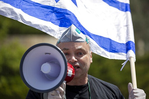 An Israeli supporter of Prime Minister Benjamin Netanyahu protests in front Israel's Supreme Court, in Jerusalem, Tuesday, March 24, 2020. Israel appeared on the verge of a constitutional crisis Tuesday as top members of Benjamin Netanyahu's Likud urged their party colleague and parliament speaker to defy a Supreme Court order to hold an election for the prime minister's successor. (AP Photo/Ariel Schalit)