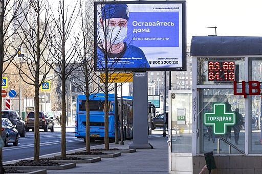 An electronic billboard showing a doctor wearing a medical mask with the words reading &quot;Stay home, it will save a life&quot; in a street in Moscow, Russia, Wednesday, March 25, 2020. Putin has postponed a nationwide vote on proposed constitutional amendments that include a change that would allow him to seek another term in power. He also announced during a televised address to the nation that the government doesn't want Russians except those working in essential sectors to come to work next week. He said that stores, pharmacies and banks will stay open. (AP Photo/Alexander Zemlianichenko)