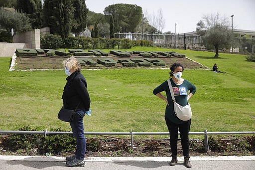 Israelis stand during a protest against Prime Minister Benjamin Netanyahu outside the national parliament in Jerusalem, Monday, March 23, 2020. The opposition has accused Netanyahu of using the coronavirus crisis as cover to undermine the country's democratic institutions. With the country in near-shutdown mode, Netanyahu has already managed to postpone his own pending criminal trial and authorize unprecedented electronic surveillance of Israeli citizens. (AP Photo/Sebastian Scheiner)