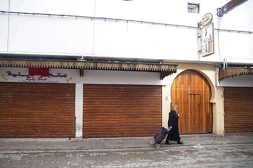 A woman pushes a trolley past closed shops in the usually bustling Medina of Rabat, on the day when Morocco declared a health emergency and further limited movement to prevent the spread of coronavirus, in Rabat, Morocco, Friday, March 20, 2020. For most people, the new coronavirus causes only mild or moderate symptoms, such as fever and cough. For some, especially older adults and people with existing health problems, it can cause more severe illness, including pneumonia. (AP Photo/Mosa'ab Elshamy)