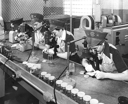 FILE - In this Feb. 10, 1943, file photo, employees of International Harvester inspect ball bearings in Chicago, the smallest being one eighth of an inch in diameter. The bearings must be sorted according to size within 25 millionths of an inch. Not since World War II when factories converted from making automobiles to making tanks, Jeeps and torpedos has the entire nation been asked to truly sacrifice for a greater good. (AP Photo, File)