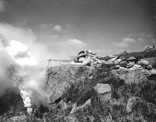 FILE - In this May 21, 1942 file photo, sniping from a rocky Irish hilltop, American troops man their Browning automatics and M-1 rifles through a haze of smoke screen during invasion maneuvers, in Ireland. Not since World War II, when people carried Ration Books, when buying cars, firewood and nylon was restricted, when men were drafted and women volunteered in the war effort, has the entire nation been asked to truly sacrifice for a greater good. (AP Photo, File)