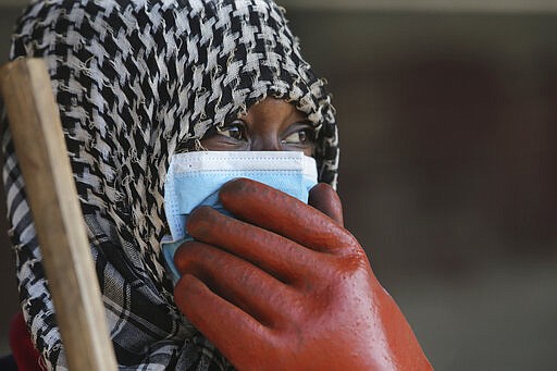 A council worker wears a face mask while cleaning the streets in Harare, Zimbabwe, Wednesday, March 25, 2020. Zimbabwe's public hospital doctors went on strike Wednesday over what they called a lack of adequate protective gear as the coronavirus begins to spread in a country whose health system has almost collapsed.  The new coronavirus causes mild or moderate symptoms for most people, but for some, especially older adults and people with existing health problems, it can cause more severe illness or death. (AP Photo/Tsvangirayi Mukwazhi) ///