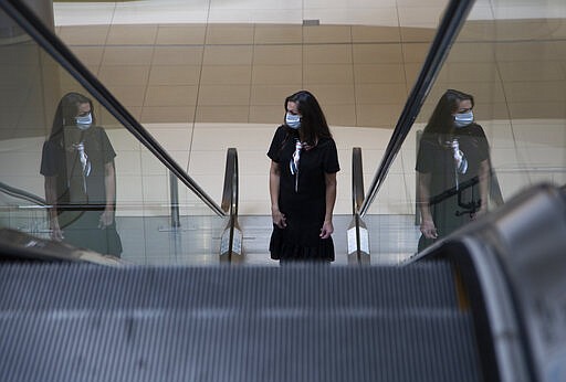 A masked shopper leaves an almost deserted Sandton City Mall in Johannesburg, Wednesday, March 25, 2020, before the country of 57 million people, will go into a nationwide lockdown for 21 days from Thursday to fight the spread of the new coronavirus. The new coronavirus causes mild or moderate symptoms for most people, but for some, especially older adults and people with existing health problems, it can cause more severe illness or death. (AP Photo/Denis Farrell)