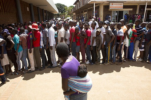 People join a queue to buy maize meal at a supermarket in Harare, Zimbabwe, Wednesday, March 25, 2020. 
 Zimbabwe's public hospital doctors went on strike Wednesday over what they called a lack of adequate protective gear as the coronavirus begins to spread in a country whose health system has almost collapsed.  The new coronavirus causes mild or moderate symptoms for most people, but for some, especially older adults and people with existing health problems, it can cause more severe illness or death. (AP Photo/Tsvangirayi Mukwazhi)