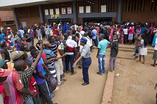 Zimbabwean police control a crowd that had gathered to buy maize meal at a supermarket in Harare, Zimbabwe, Wednesday, March 25, 2020. Zimbabwe's public hospital doctors went on strike Wednesday over what they called a lack of adequate protective gear as the coronavirus begins to spread in a country whose health system has almost collapsed.  The new coronavirus causes mild or moderate symptoms for most people, but for some, especially older adults and people with existing health problems, it can cause more severe illness or death. (AP Photo/Tsvangirayi Mukwazhi)