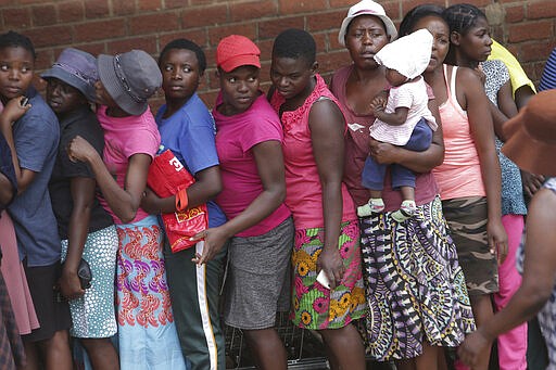 Women are seen in a queue for maize meal at a supermarket in Harare, Zimbabwe, Wednesday, March 25, 2020. 
Zimbabwe's public hospital doctors went on strike Wednesday over what they called a lack of adequate protective gear as the coronavirus begins to spread in a country whose health system has almost collapsed.  The new coronavirus causes mild or moderate symptoms for most people, but for some, especially older adults and people with existing health problems, it can cause more severe illness or death.(AP Photo/Tsvangirayi Mukwazhi)