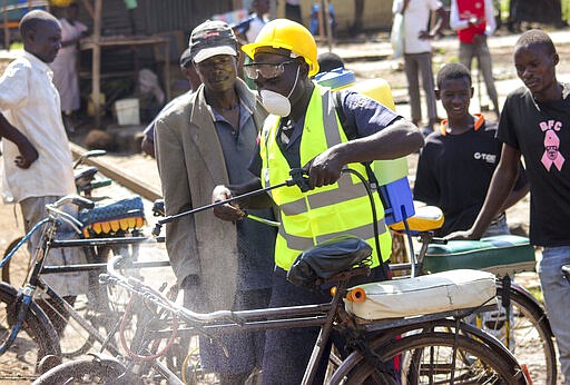 A man sprays disinfectant on a bicycle taxi in the Kibuye Market area of Kisumu in western Kenya Wednesday, March 25, 2020. The new coronavirus causes mild or moderate symptoms for most people, but for some, especially older adults and people with existing health problems, it can cause more severe illness or death. (AP Photo/Amos Aura)