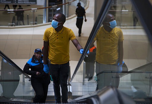 A masked shopper leaves leaves an almost deserted Sandton City Mall in Johannesburg, Wednesday, March 25, 2020 before the country of 57 million people, will go into a nationwide lockdown for 21 days from Thursday to fight the spread of the new coronavirus. The new coronavirus causes mild or moderate symptoms for most people, but for some, especially older adults and people with existing health problems, it can cause more severe illness or death. (AP Photo/Denis Farrell)