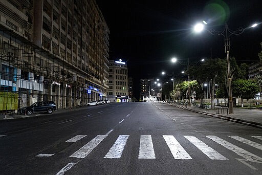 In this Tuesday March 24, 2020, photo, a street is empty in Dakar, Senegal as an 8pm to 6am curfew is enforced in an effort to fight the coronavirus outbreak. The new coronavirus causes mild or moderate symptoms for most people, but for some, especially older adults and people with existing health problems, it can cause more severe illness or death. (AP Photo/Sylvain Cherkaoui)