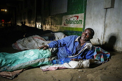 In this photo taken Tuesday, March 24, 2020, a homeless person prepares to sleep next to others on the side of a road in the Mathare slum, or informal settlement, of Nairobi, Kenya. Many slum residents say staying at home or social-distancing is impossible for those who live hand to mouth, receiving daily wages for informal work with no food or economic assistance from the government, as is maintaining sanitation where a pit latrine can be shared by over 50 people. The new coronavirus causes mild or moderate symptoms for most people, but for some, especially older adults and people with existing health problems, it can cause more severe illness or death. (AP Photo/Brian Inganga)