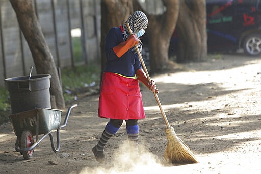 A council worker wears a face mask while cleaning the streets in Harare, Zimbabwe, Wednesday, March 25, 2020. Zimbabwe's public hospital doctors went on strike Wednesday over what they called a lack of adequate protective gear as the coronavirus begins to spread in a country whose health system has almost collapsed.  The new coronavirus causes mild or moderate symptoms for most people, but for some, especially older adults and people with existing health problems, it can cause more severe illness or death. (AP Photo/Tsvangirayi Mukwazhi)