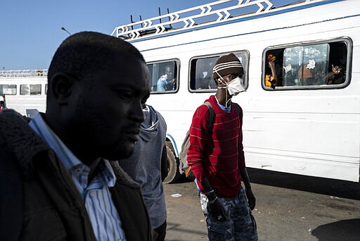 Travelers, some wearing a protective mask, take a bus from the Colobane Bus Station in Dakar, Senegal, Tuesday March 24, 2020. The transport Ministry has announced a limit to the number of passengers to carried in a bus at one time, to prevent the risk of contamination by the Coronavirus. The highly contagious COVID-19 coronavirus can cause mild symptoms, but for some it can cause severe illness including pneumonia that may force admission to hospital.  (AP Photo/Sylvain Cherkaoui)