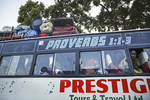 In this photo taken Tuesday, March 24, 2020, a passenger looks out from a bus transporting people from the city to the countryside, where some feel they will be safer, in the Mathare slum, or informal settlement, of Nairobi, Kenya. Many slum residents say staying at home or social-distancing is impossible for those who live hand to mouth, receiving daily wages for informal work with no food or economic assistance from the government, as is maintaining sanitation where a pit latrine can be shared by over 50 people. The new coronavirus causes mild or moderate symptoms for most people, but for some, especially older adults and people with existing health problems, it can cause more severe illness or death. (AP Photo/Brian Inganga)