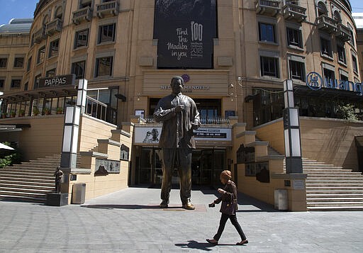 A statue of former President Nelson Mandela looks over a deserted Mandela Square in Johannesburg, Wednesday, March 25, 2020, before the country of 57 million people, will go into a nationwide lockdown for 21 days from Thursday to fight the spread of the new coronavirus. The new coronavirus causes mild or moderate symptoms for most people, but for some, especially older adults and people with existing health problems, it can cause more severe illness or death. (AP Photo/Denis Farrell)