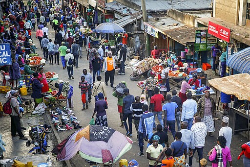 In this photo taken Tuesday, March 24, 2020, residents walk through a small and crowded market where social-distancing is difficult, in the Mathare slum, or informal settlement, of Nairobi, Kenya. Many slum residents say staying at home or social-distancing is impossible for those who live hand to mouth, receiving daily wages for informal work with no food or economic assistance from the government, as is maintaining sanitation where a pit latrine can be shared by over 50 people. The new coronavirus causes mild or moderate symptoms for most people, but for some, especially older adults and people with existing health problems, it can cause more severe illness or death. (AP Photo/Brian Inganga)