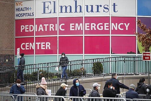 A woman exits a COVID-19 testing site while hundreds wait in line at Elmhurst Hospital Center, Wednesday, March 25, 2020, in New York. Gov. Andrew Cuomo sounded his most dire warning yet about the coronavirus pandemic Tuesday, saying the infection rate in New York is accelerating and the state could be as close as two weeks away from a crisis that sees 40,000 people in intensive care. Such a surge would overwhelm hospitals, which now have just 3,000 intensive care unit beds statewide. (AP Photo/John Minchillo)