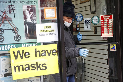 A customer leaves a shop advertising personal protective equipment near Elmhurst Hospital Center, Wednesday, March 25, 2020, in New York. Gov. Andrew Cuomo sounded his most dire warning yet about the coronavirus pandemic Tuesday, saying the infection rate in New York is accelerating and the state could be as close as two weeks away from a crisis that sees 40,000 people in intensive care. Such a surge would overwhelm hospitals, which now have just 3,000 intensive care unit beds statewide. (AP Photo/John Minchillo)