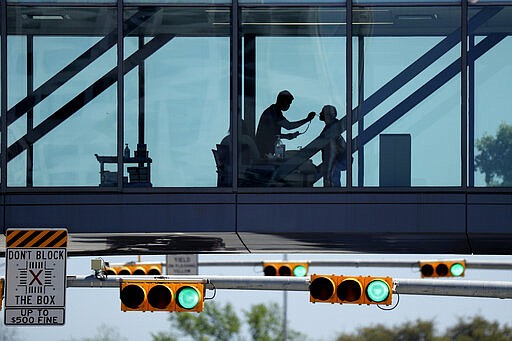 A woman has her temperature taken at a control point on a covered footbridge to be screened for symptoms before entering the Dell Deton Medical Center at the University of Texas in Austin, Texas, Wednesday, March 25, 2020. Austin is under Stay-at-Home orders to help battle the effects of COVID-19. (AP Photo/Eric Gay)