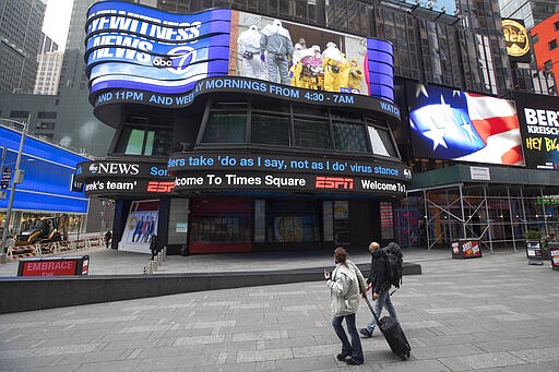 A couple looks at the ABC News video screen showing coverage of a coronavirus outbreak in Woodbridge, N.J., Wednesday, March 25, 2020, in New York's Times Square. The number of people hospitalized with COVID-19 in New York climbed to 3,800, with close to 900 in intensive care, with the peak of the outbreak weeks away, Gov. Andrew Cuomo said Wednesday. The new coronavirus causes mild or moderate symptoms for most people, but for some, especially older adults and people with existing health problems, it can cause more severe illness or death. (AP Photo/Mary Altaffer)